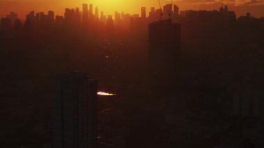 Manila ufuk çizgisi gün doğumunda, altın ışıkla aydınlatılan güneş şehrin üzerinden yükselirken, Filipinlerdeki kentsel yaşamı ve mimariyi gözler önüne seriyor..