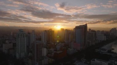 Hava görüntüsü, Manila, Filipinler 'in canlı şehir manzarasında güneşin doğuşunu gösteriyor. Gökyüzüne ve gökyüzüne sıcak renkler döküyor..