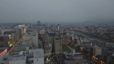 İleriye doğru alacakaranlıkta şehrin üzerinde uçun. Metropolis 'te yağmurlu bir akşam. Şehir merkezindeki çok katlı binalar. Kyoto, Japonya, 10 Şubat 2024