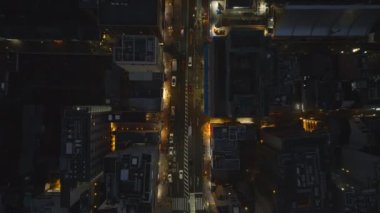 Gece şehrinin üzerinde yükseklere uç. Şehir merkezindeki çok katlı binalar arasında caddelerde giden araçların yüksek açılı görüntüsü. Kyoto, Japonya.