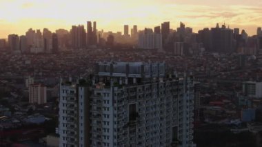 Manila silueti üzerinde sakin bir gündoğumu görüntüsü, terasın üstünde bir konut binası ve sıcak şehir manzarası var. Şehir manzarası ve seyahat içeriği.
