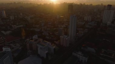 Gün doğumunda Manila şehir manzarası. Altın güneş ışığı, yükselen binaları aydınlatarak pitoresk bir şehir manzarası yaratıyor..