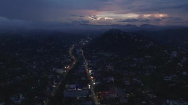 Gece karanlığında Kandy, Sri Lanka 'nın büyüleyici hava manzarası şehrin ışıklarını ve dağ siluetlerini alacakaranlık gökyüzüne karşı sergiliyor..