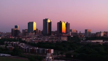 Fort Worth, Teksas alacakaranlıkta gökyüzü alacakaranlığa karşı günbatımının renklerini yansıtan yüksek binalarla gökyüzü. .