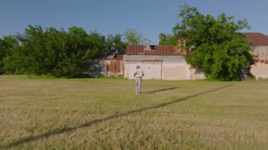 İşçi, Amerika 'nın kırsal kesiminde, yemyeşil ve güneşli yaz günlerinde ağaçların arasına kurulmuş yaşlı bir binaya yaklaşır..