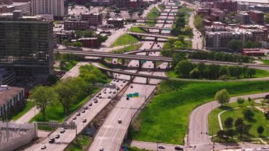 Kansas 'ta yeşil alanları ve şehir binaları olan yoğun bir otoyol kavşağının enerjik hava görüntüsü. Şehrin canlı atmosferine ve çağdaş altyapısına yukarıdan tanık olun.