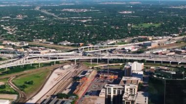 Büyük Amerikan şehirleri otoyolu kavşakları ve çevreleyen binaları aydınlatıyor ve mavi gökyüzüne karşı havadan bir bakış açısıyla parklar..