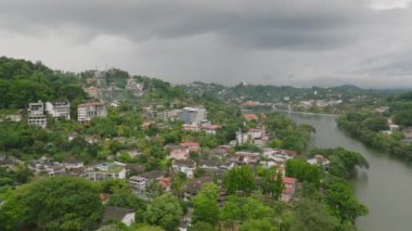 Kandy, Sri Lanka 'nın yemyeşil, kentsel manzarası ve bulutlu gökyüzünün altında sakin bir göl Asya' da tipik bir tropikal manzara..