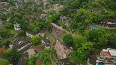 Kandy, Sri Lanka 'da bir yerleşim bölgesinin resimli manzarasında tipik evler ve tropikal ağaçlar sergilenir..