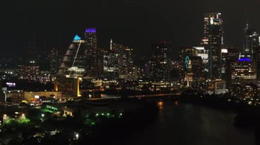 Austin, Teksas şehir manzarası. Aydınlatılmış gökdelenler, canlı ışıklar ve şehrin parıltısını yansıtan sakin bir nehir..