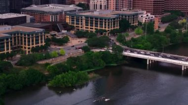 Austin şehir merkezinin hareketli manzarası köprü trafiğini ve nehir teknelerini modern mimari ve yemyeşil alanlarda sergiliyor..