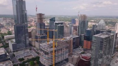 Gökdelenleri, inşaat alanları ve şehir manzarası olan Austin şehrinin hava manzarası açık bir günde. Canlı şehir hayatı ve modern mimari sergileniyor.