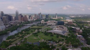 Austin, Teksas 'taki canlı parkların hava perspektifi, ünlü silueti ile, parçalı bulutlu bir zemine karşı sakin Colorado Nehri suyu.