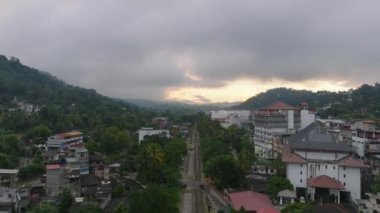 Kandy 'nin büyüleyici cazibesi, şafak vakti Sri Lanka. Bu hava manzarası bulutlu bir gökyüzünün altındaki şehirlerin mimarisini, yeşilliğini ve sisli dağları vurgular..