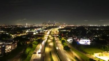 Houston otobanındaki hareketli gece trafiğinin aşırı hızlanması göz kamaştırıcı ışık yolları ve şehrin ufuk çizgisi bu büyük Amerikan şehrinin uzaklığında parlıyor..
