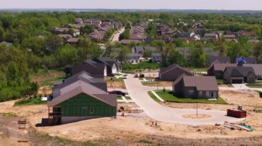 Amerikan mahallesinde inşaat halindeki banliyö evlerinin havadan görüntüsü. Yeşil arazi ve evler kıvrımlı bir caddeye dizilmiş..