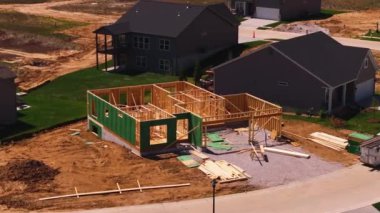 Banliyö mahallesinde inşa edilen ahşap bir evin havadan görünüşü, Amerika 'da inşaatın farklı aşamalarını gösteriyor..