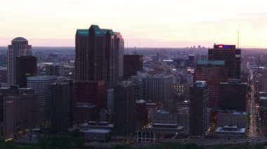 St. Louis 'in alacakaranlıkta gökyüzü manzarası, şehrin ışıkları aşağıdaki yüksek binalarda ve caddelerde parlıyor. Arka planda muhteşem bir günbatımı. St. Louis, Missouri, ABD, 10 Nisan 2024
