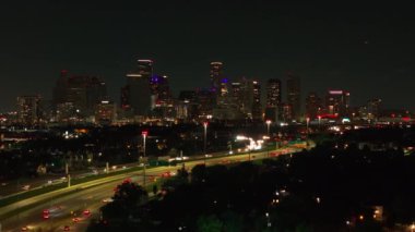 Houstons 'un gece aydınlık binalar ve işlek otoyollarla dolu gökyüzü manzarası. Dinamik şehir manzarası ve hareketli trafik akışı.
