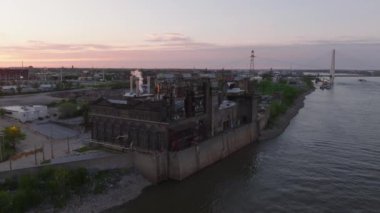 Günbatımında St. Louis 'de Mississippi Nehri' nin yanındaki Ashley Street Sanayi Evi 'nin hava manzarası hareketli bir etkinlik ve sakin bir su yolu güzelliği sergiliyor.