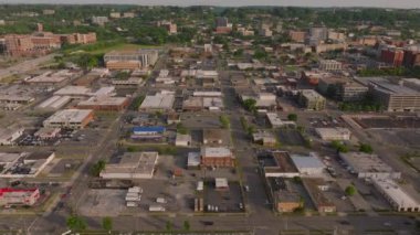Orta ölçekli bir Amerikan şehrinin ticari alanındaki alçak binaların yüksek irtifa manzarası şehir planlarını, otoparkları, caddeleri ve yeşillikleri gösteriyor.