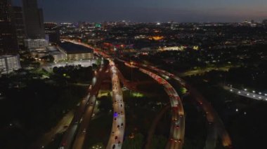 Houston karayolu trafiğinin gece hava görüntüsü, şehrin ışıkları ufuk çizgisini aydınlatıyor ve arabalar sürekli hareket halinde. Teksas 'ta dinamik şehir hayatı.