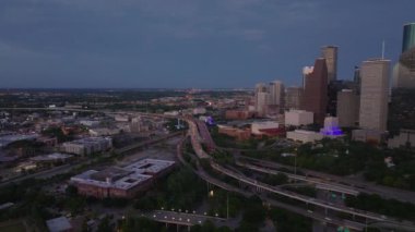 Houston ufuk çizgisi ve karayolu üstgeçitlerinin hava görüntüsü alacakaranlıkta şehir manzarasının geceye dönüşünü yakalıyor..