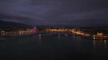 Gece Genevas 'ın rıhtımının havadan görüntüsü, şehrin ışıklarının suya yansıması. Şehir güzelliğini sergilemek için ideal..