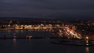 Gece Genevas rıhtımının havadan görünüşü şehrin ışıklarını ve arka plandaki Alpler 'in sudaki yansımalarını gösteriyor..