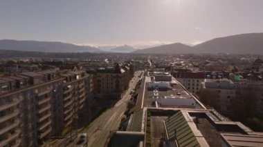 Gün batımında Cenevre 'de trafik caddesi olan canlı bir şehrin havadan görünüşü, uzaktaki binalar ve dağların yer aldığı.