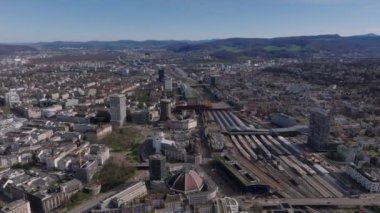 İleri, büyük kubbeyle popüler Markethalle 'nin üzerinde uçar. Çatı platformları ve çevre binaları olan tren istasyonu. Basel, İsviçre.