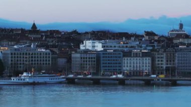 Araçlar su üzerinde yol köprüsünden geçiyor. Sabah kentinde rıhtımdaki binalar. Yolcu gemisi ortaya çıkıyor. Cenevre, İsviçre.
