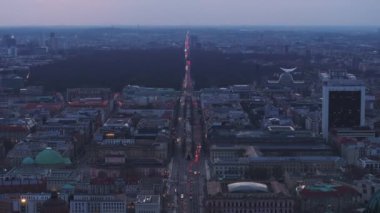 Berlins Unter den Linden Bulvarı 'nın ve Brandenburg Kapısı' nın alacakaranlıkta Tiergarten 'ın arka planında nefes kesici hava manzarası..