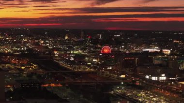 St. Louis şehrinin alacakaranlıktaki hava manzarası, renkli bir gökyüzü altında parlayan dönme dolap ve şehir manzarası, kentsel güzellikleri ve canlı şehir ışıklarını gözler önüne seriyor..