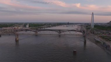 St. Louis 'deki Mississippi Nehri üzerindeki köprülerin hava manzarası, yumuşak akşam güneşi ışığı ve arka planda bir şehir silüeti. Kentsel, ulaşım ve seyahat kavramı.