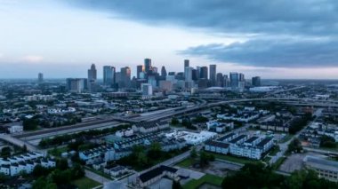 Günbatımında Houston, Teksas 'ın çarpıcı hava manzaraları, şehir siluetlerini, otoyolları ve şehir manzaralarını dramatik bir gökyüzü altında sergiliyor modern mimariyi ve hareketli şehir yaşamını aydınlatıyor..