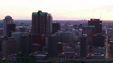 St. Louis 'in alacakaranlıkta gökyüzü manzarası, şehrin ışıkları aşağıdaki yüksek binalarda ve caddelerde parlıyor. Arka planda muhteşem bir günbatımı. St. Louis, Missouri, ABD, 10 Nisan 2024
