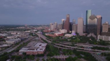 Houston 'ın alacakaranlıktaki gökdelenleri, otoyolları ve şehir manzarasını gösteren gökyüzü manzarası modern mimariyi ve şehir hayatını ön plana çıkarıyor..