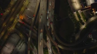 Bir Amerikan şehrinde geceleyin hareketli bir otoyol kavşağının havadan görünüşü. Parlak yollar, arabalar ve binalar canlı bir gece manzarası oluşturur..