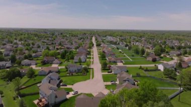 Amerika 'da sakin bir yerleşim bölgesinin havadan görünüşü, güneşli mavi gökyüzüne karşı düzenli evler ve gür yeşillikler sergiliyor..