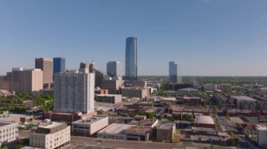Oklahoma Citys şehir merkezindeki gökyüzü açık bir gün. Şehir binaları mavi gökyüzü zeminine karşı, şehir mimarisi ve canlı şehir hayatı sergileniyor. Oklahoma City, ABD