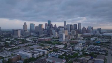 Houston şehir merkezinin dinamik şehir manzarası gökdelenlerini ve çevresindeki alçak binaları dramatik bulutlu gökyüzü altında sergiliyor..