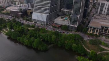 Austin, Teksas şehir merkezindeki nehir kenarındaki çağdaş gökdelenlerin ve canlı yeşilliklerin havadan görüntüsü. Şehir manzarası ve şehir manzarası için ideal. Austin, ABD, 10 Nisan 2024