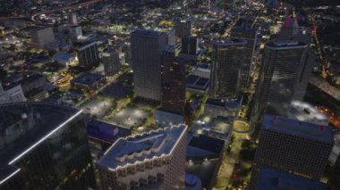 Houston şehir merkezinin gece hava görüntüsü, parıldayan gökdelenler, hareketli sokaklar, ve hareketli şehir manzarası.