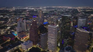 Geceleri Houston şehir merkezinin havadan görünüşü aydınlanmış şehir manzarasını ve yukarıdan gelen çelik ve camdan yapılmış modern mimari gökdelenleri gösteriyor..