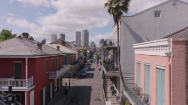 New Orleans 'taki Fransız Mahallesi' nin canlı caddeleri ve tarihi binaları, gökdelenler uzak mesafede parçalı bulutlu bir gökyüzüne karşı.
