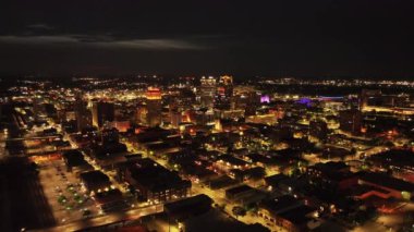 Birmingham, ABD 'nin gece hava görüntüsü, ışıldayan sokaklar, binalar ve renkli ışıklarla dolu şehir manzarasını yakalıyor, kentsel ufuk çizgisini vurguluyor.