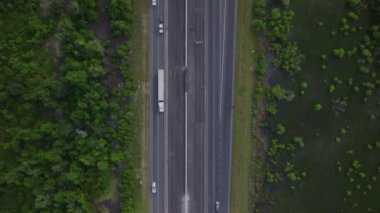 Amerika 'nın yemyeşil ormanlarıyla çevrili işlek bir otoyoldaki araçların hava görüntüsü. Ulaşım, seyahat ve doğa kavramları.