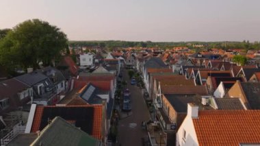 Gün batımında hoş bir Hollanda köyü, rahat evler, kırmızı çatılar, ve caddeler boyunca park edilmiş arabalar sıcak ışıkta parlıyor..