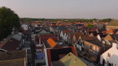 Huzurlu bir günbatımında canlı yeşilliklerle çevrili kırmızı çatılı evleri olan bir Hollanda köyünün büyüleyici cazibesi..